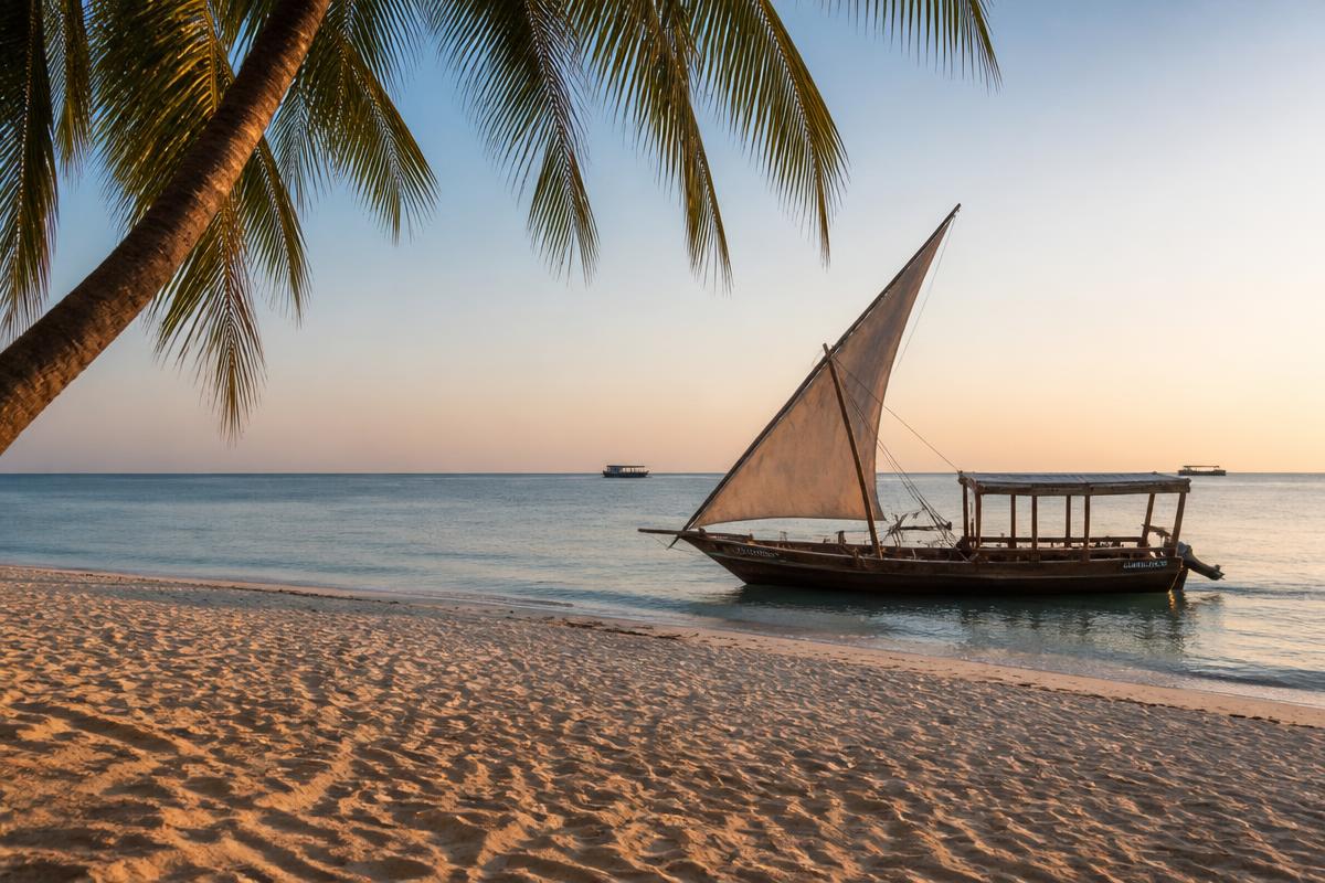 Wooden dhow on the white sand of a Zanzibar beach at golden hour